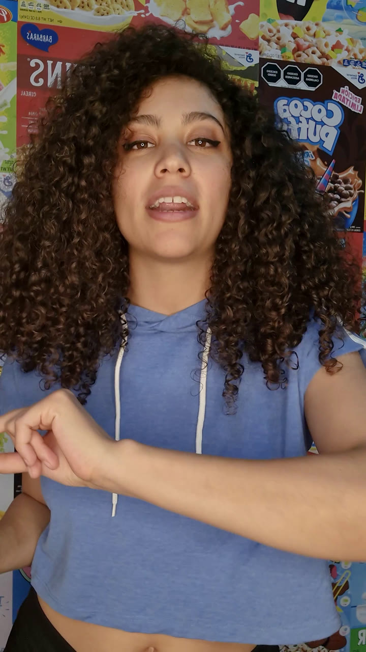 Original photo: a woman with voluminous curly hair in front of a wall of colorful cereal boxes