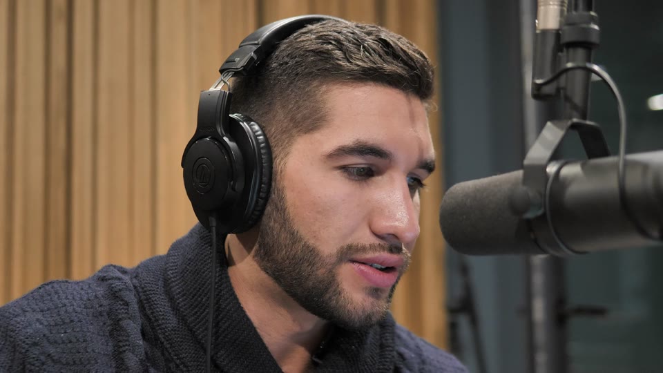 Original video frame: a podcast host in headphones beside a studio microphone