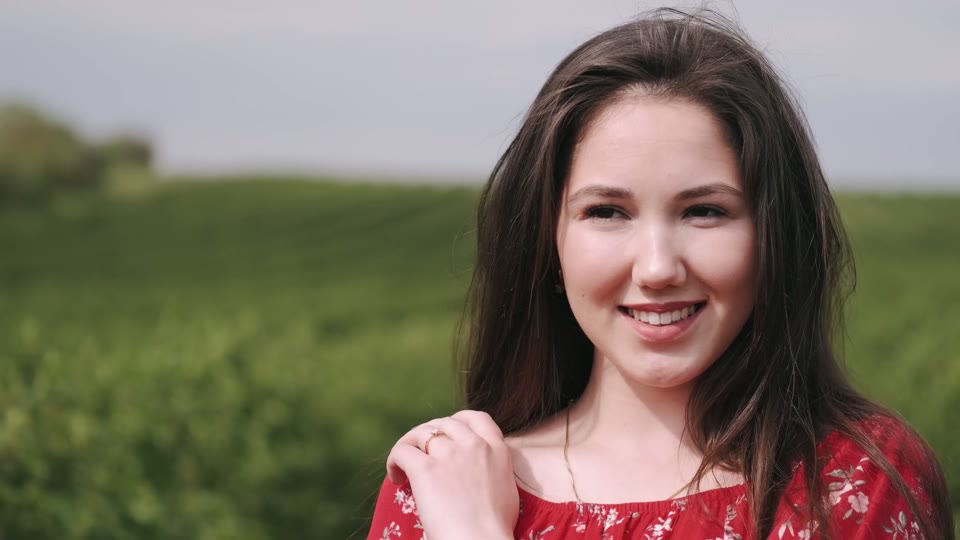 Original video frame: a woman outdoors with a green landscape behind her